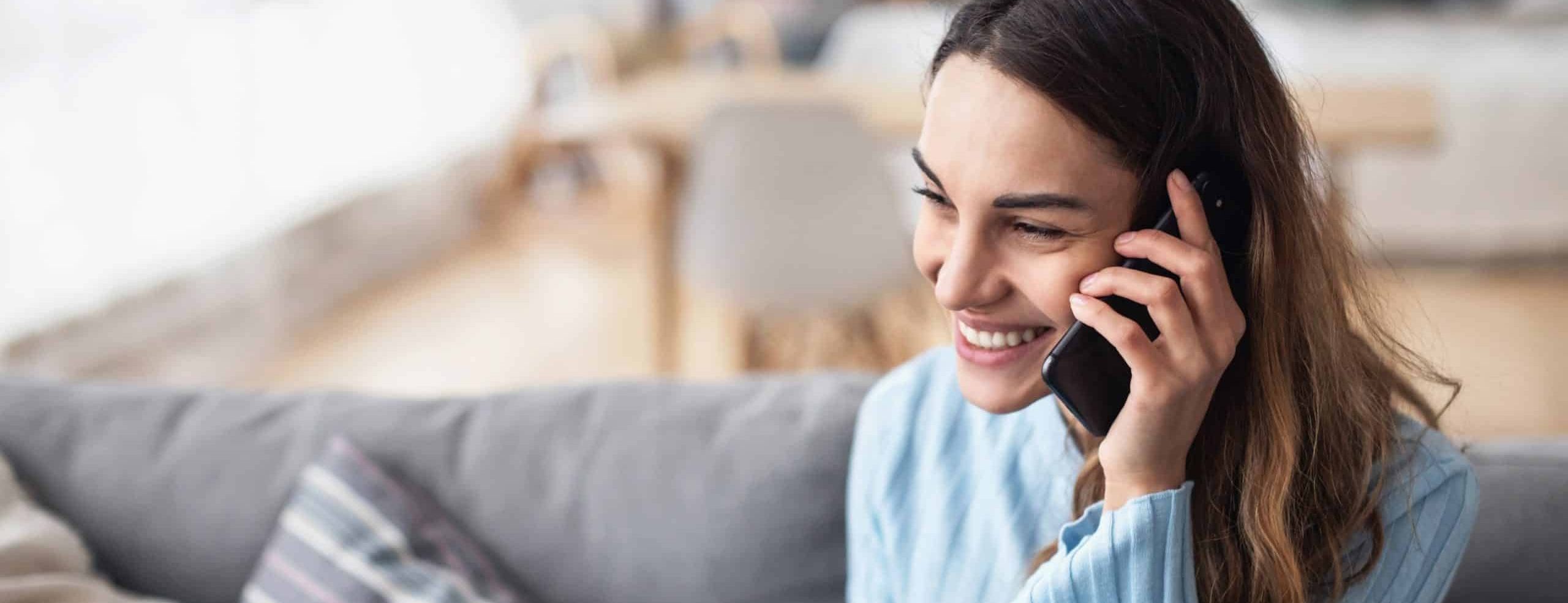 Attractive smiling woman talking on the phone at home. Technology, communication and coziness concept.